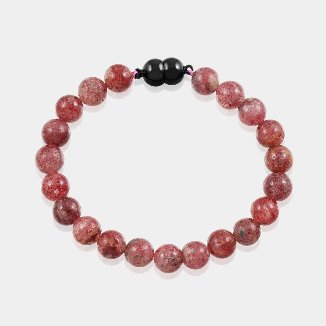 A detailed shot of the magnetic lock mechanism on the strawberry quartz gemstone bracelet, highlighting its functional design with brass accents.